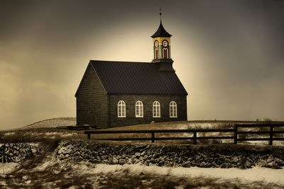 Building on field against sky during winter