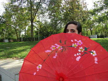 Portrait of woman standing by red flowering plants