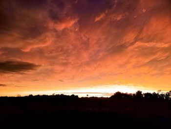 Silhouette landscape against dramatic sky during sunset