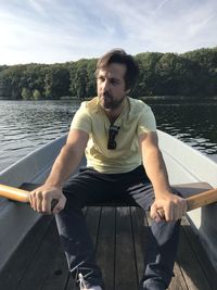 Man in boat on lake against sky