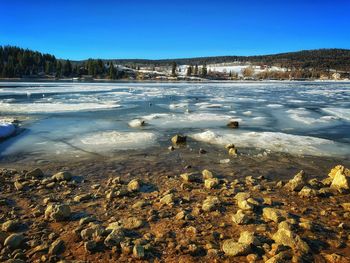 Scenic view of snow covered land against clear blue sky