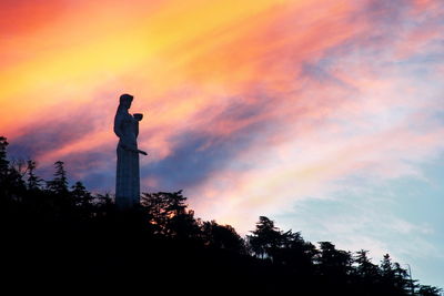 Low angle view of silhouette statue against dramatic sky