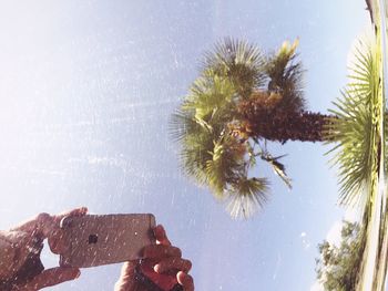 Close-up of hand holding water against sky