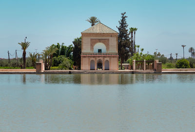 Building by lake against clear blue sky