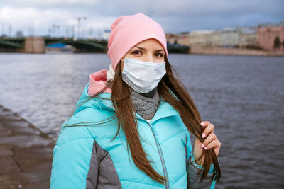 Portrait of woman wearing mask standing by river