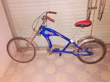 Side view of bicycle parked against wall