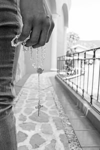 Midsection of person holding rosary beads on footpath