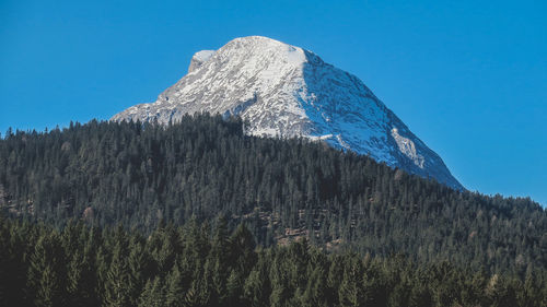 Low angle view of snowcapped mountain against clear blue sky