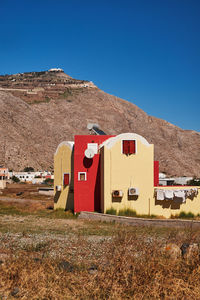 House on field against clear blue sky