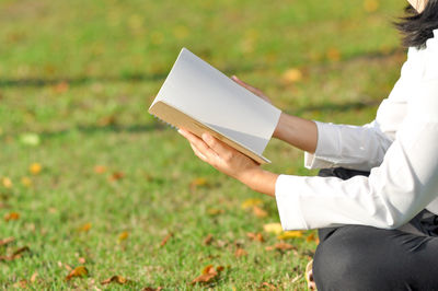 Midsection of woman holding umbrella on field