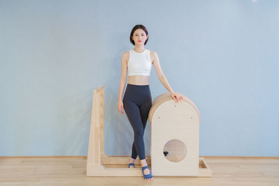 Full length of young woman standing against wall