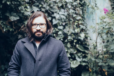 Portrait of young man standing against plants