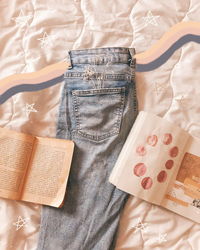 Directly above shot of jeans and books on bed