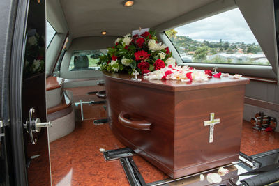 Closeup shot of a funeral casket or coffin in a hearse or chapel or burial at cemetery
