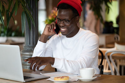 Man using phone by laptop on table