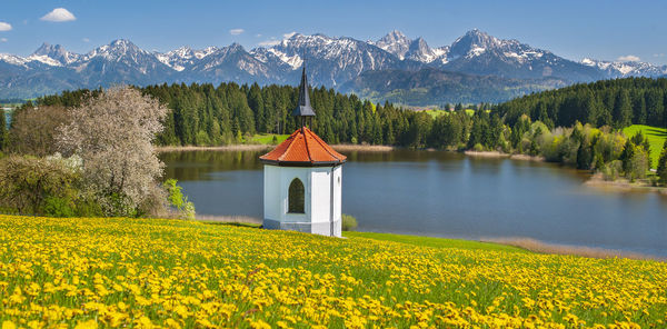 Panoramic landscape with chapel, mountains and meadow at springtime
