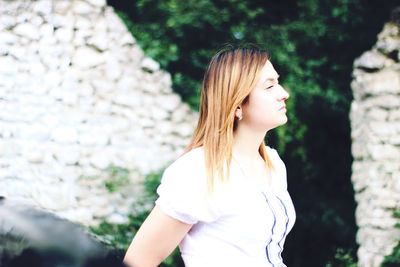 Close-up of young woman standing against tree