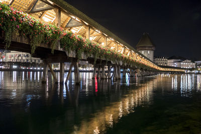 Illuminated bridge over river against sky at night