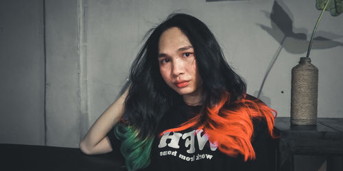 Portrait of a young woman standing against wall