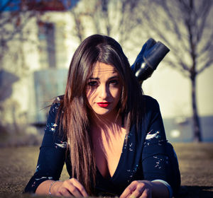 Portrait of young woman lying on field at park