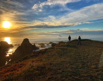 People on beach against sky during sunset