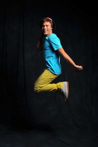 Portrait of happy girl dancing against black background