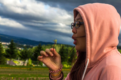 Side view of woman blowing over dandelion