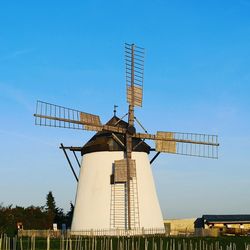 Low angle view of traditional windmill against clear blue sky