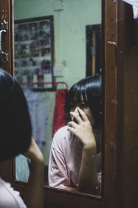 Rear view of woman looking through window