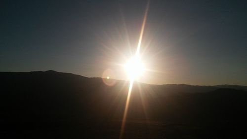 Sun shining through clouds over mountains