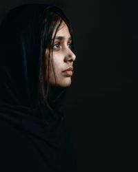 Thoughtful young woman looking away against black background