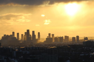 Modern buildings in city against sky during sunset