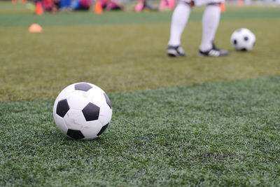 Low section of person playing soccer ball on grass