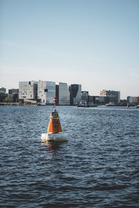 Nautical vessel on sea by buildings against clear sky