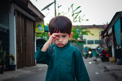 Portrait of boy standing against built structure