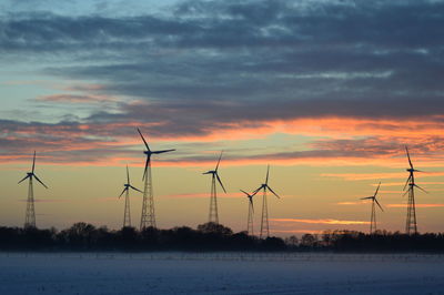 Silhouette of wind turbine against sky during sunset