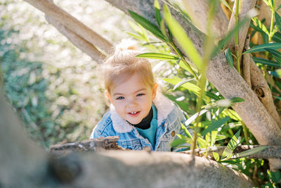 Portrait of young woman standing against plants