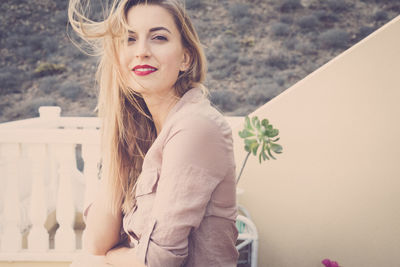 Side view portrait of beautiful woman with tousled hair sitting outdoors