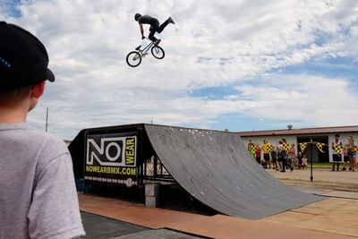 Man with bicycle in mid-air against sky