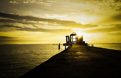 Pier over sea against sky during sunset