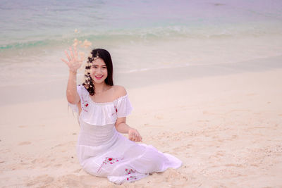 Portrait of smiling beautiful woman sitting at beach