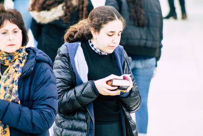 Woman looking at camera while standing on mobile phone