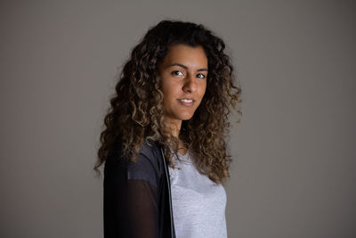 Portrait of young woman standing against wall