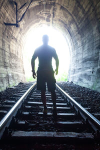 Rear view of silhouette man standing in tunnel