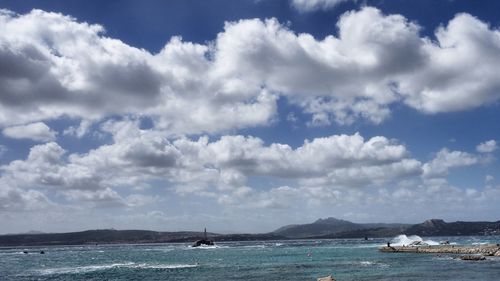 Boat sailing in sea against cloudy sky