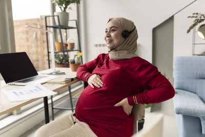 Smiling pregnant businesswoman freelancing at home