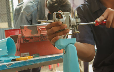 Midsection of man working on machine at workshop