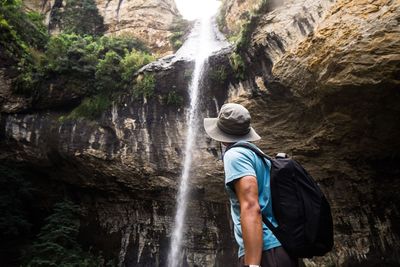 Man standing against waterfall