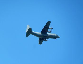 Low angle view of airplane against clear blue sky