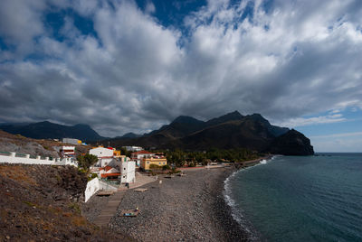 Scenic view of sea by buildings against sky